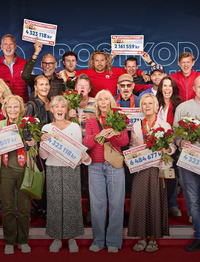A group of people celebrating with large lottery checks and flowers, standing on a stage with a sign in the background.
